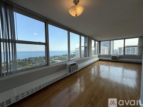 A large empty room with wooden floors and large windows overlooking the city.