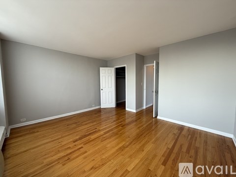A room with wooden flooring and white walls, with a door on the left and a glass door on the right.