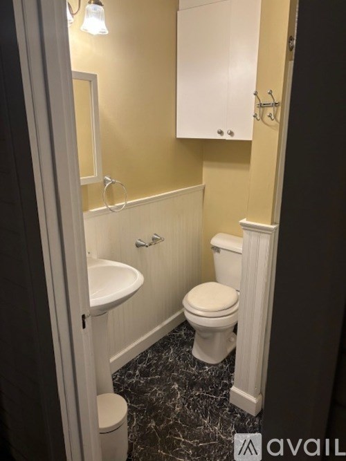 A bathroom with a toilet, sink, and cabinet.