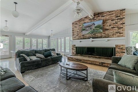 A living room with a grey couch, a coffee table, and a fireplace with a painting above it.