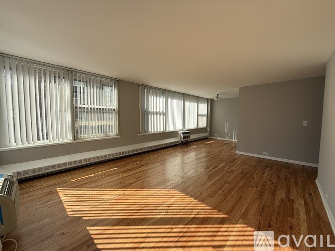 A spacious room with wooden floors and large windows allowing natural light to enter.