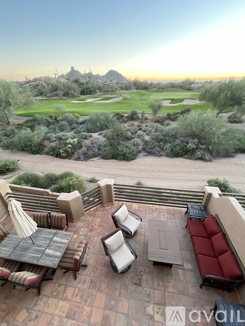 A patio with a table and chairs overlooking a golf course.