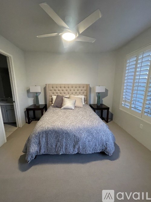 A bedroom with a large bed and a ceiling fan.