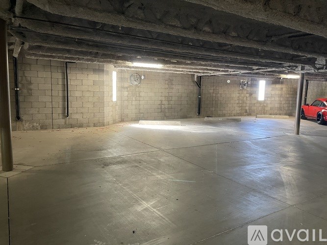 A spacious garage with a red car on the right side.