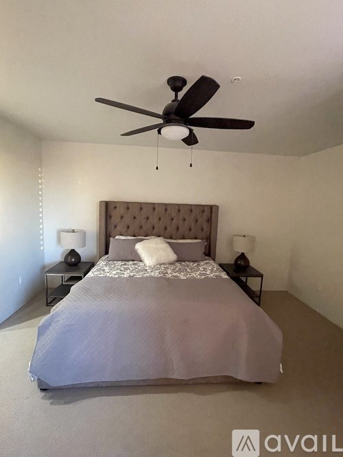 A bedroom with a large bed and a ceiling fan.