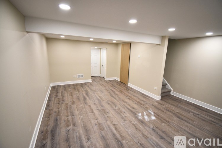 A room with wooden flooring and a door in the background.