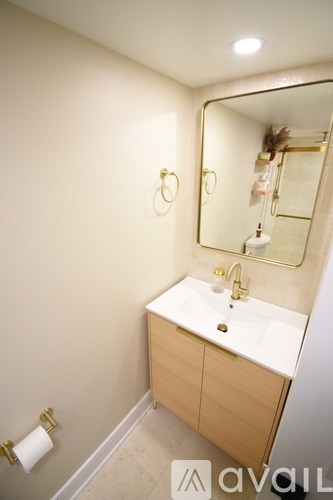 A bathroom with a sink, mirror, and toilet paper holder.