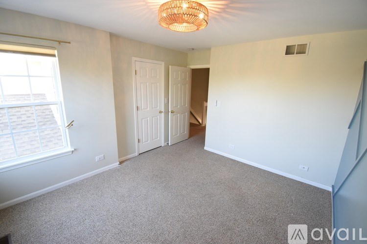 A room with a carpeted floor, a window with blinds, and a ceiling light.