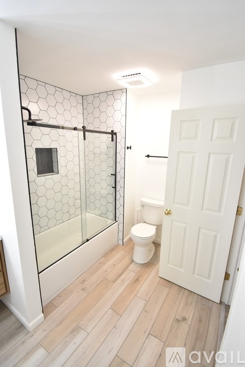 A white door is in a bathroom with a glass shower stall.