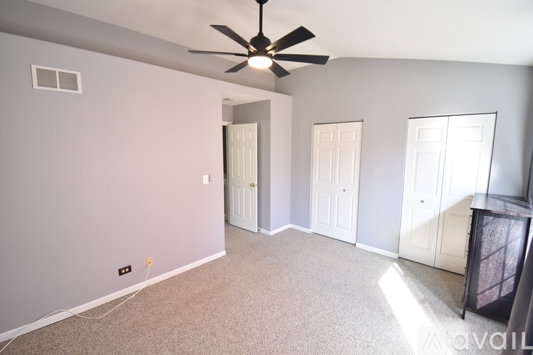 A spacious room with a ceiling fan and carpeted floor.