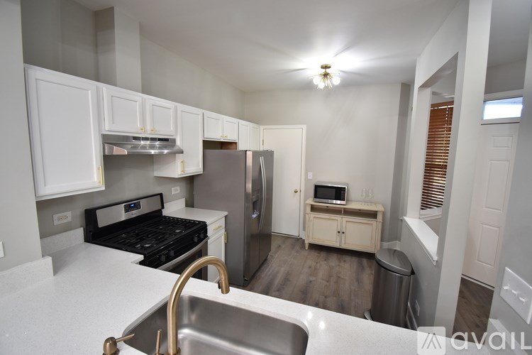A kitchen with a stove, sink, and refrigerator.
