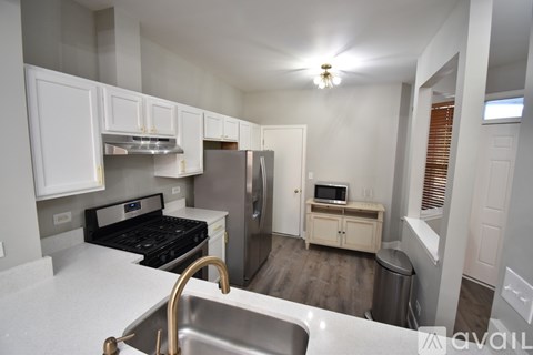 A kitchen with a stove, sink, and refrigerator.