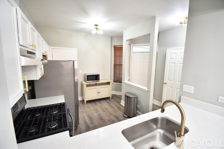 A kitchen with a stove, sink, and cabinets.