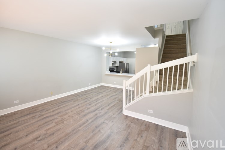 A spacious room with wooden flooring and a staircase leading to another level.
