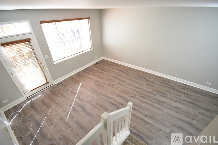 A room with wooden flooring and a window with blinds.