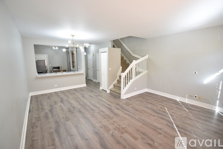 A spacious room with wooden flooring and a staircase leading to another level.