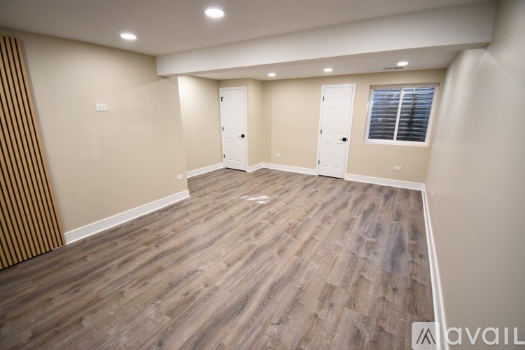 A spacious room with wooden flooring and two white doors.