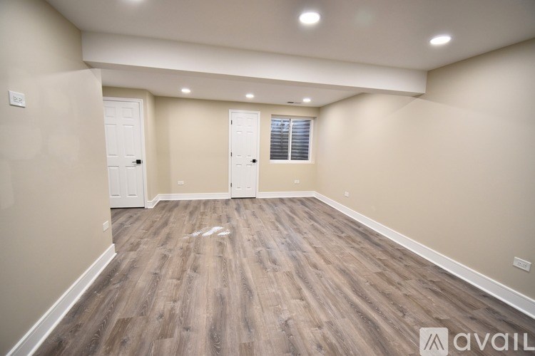 A spacious room with wooden flooring and white walls is available for rent.