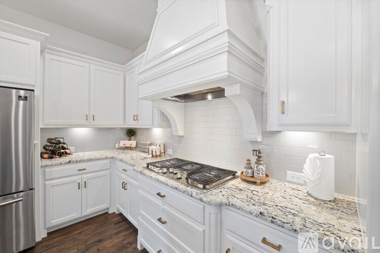 A kitchen with white cabinets and a marble countertop.