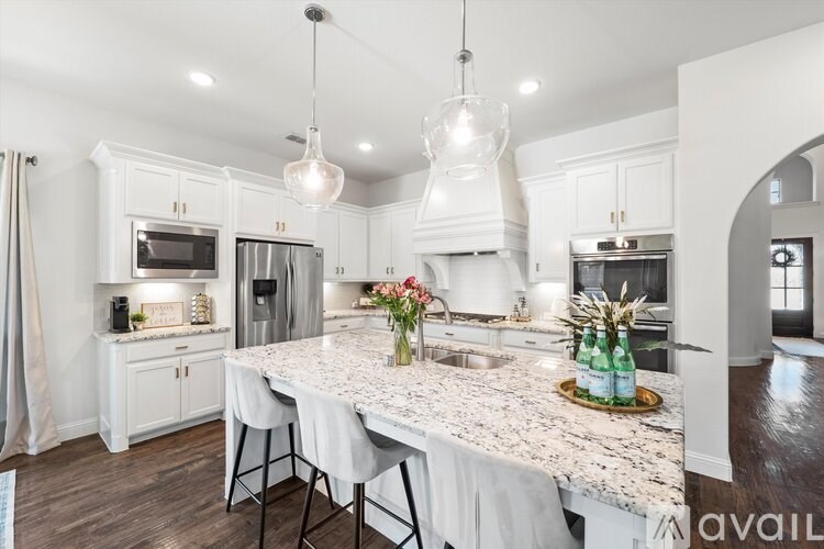A kitchen with a marble countertop and white cabinets.