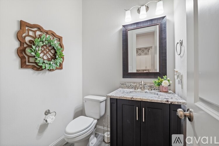 A bathroom with a toilet, sink, and a mirror.