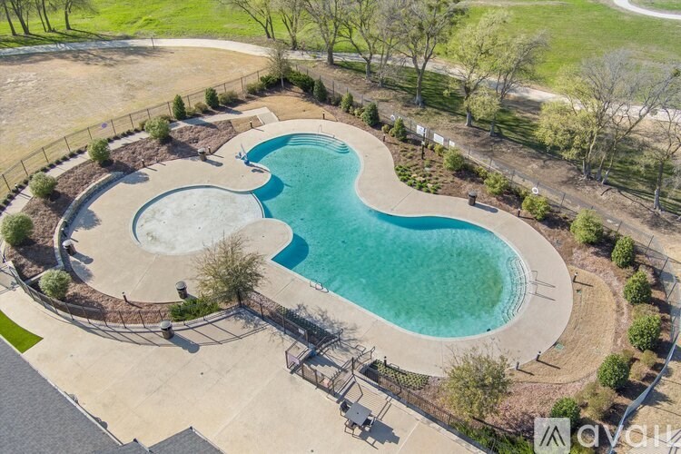 An aerial view of a swimming pool surrounded by a concrete patio and a metal fence.