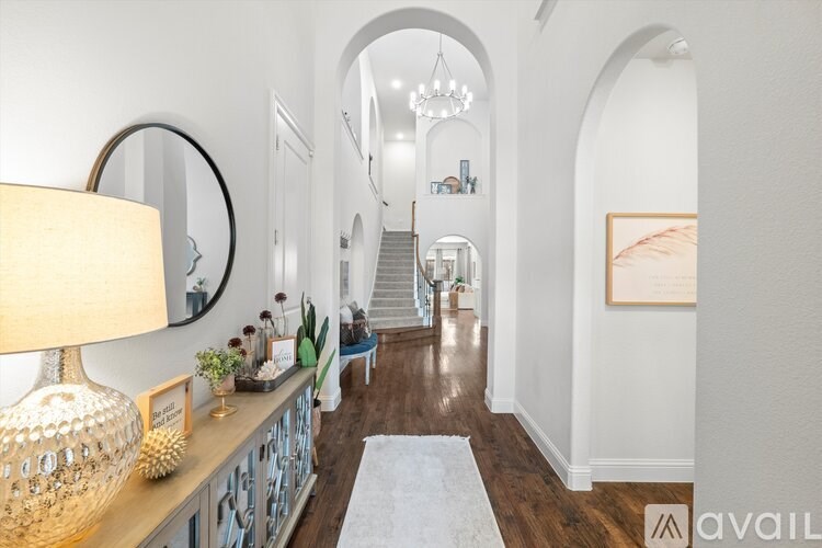 A hallway with a wooden floor and a white wall with a framed picture on it.