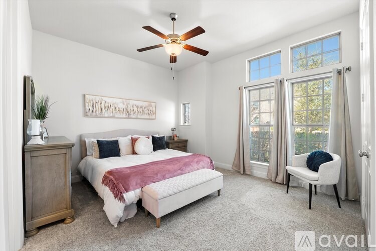 A bedroom with a bed, chair, and a ceiling fan.