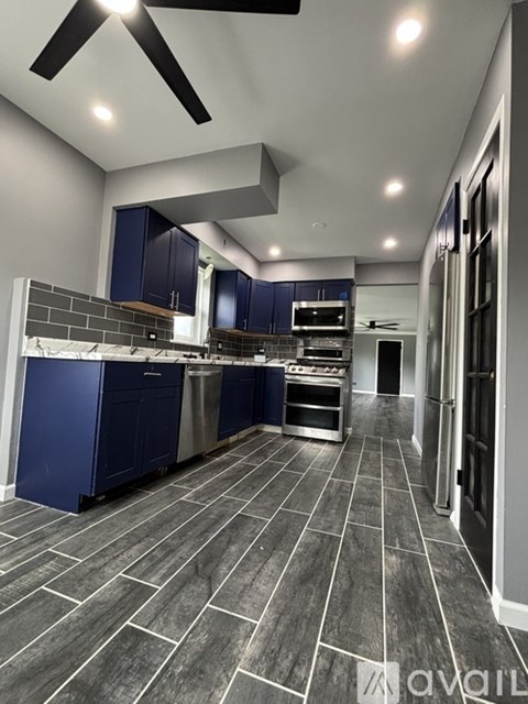A modern kitchen with blue cabinets and a tiled floor.