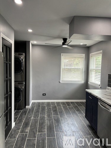 A modern kitchen with a washing machine and a fan.