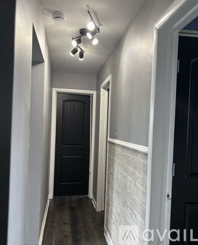 A hallway with a black door and white walls.