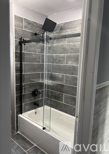 A modern bathroom with a glass shower enclosure and a white bathtub.