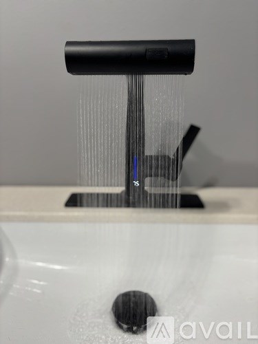 A black faucet with water flowing from it.