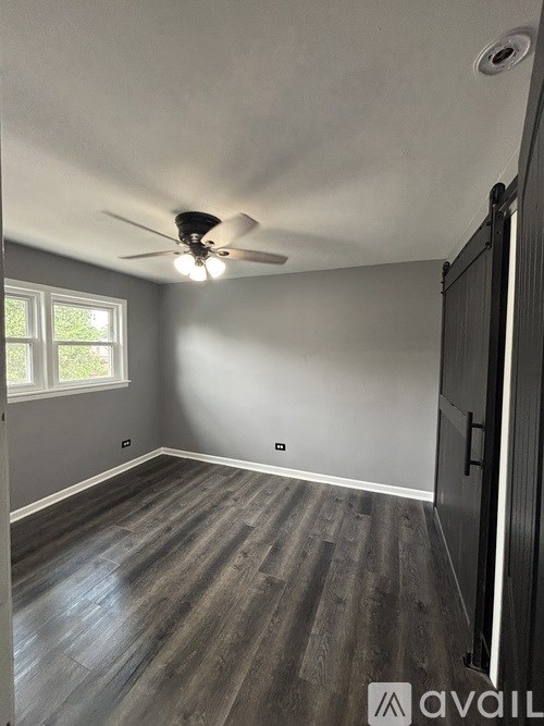 A room with a ceiling fan and wooden flooring.