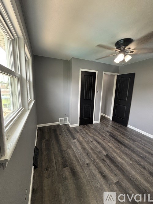 A room with a ceiling fan and wooden flooring.