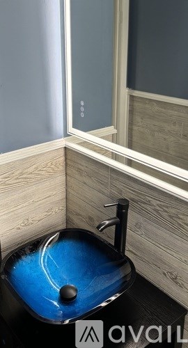 A blue toilet with a black seat cover and a black flush handle.