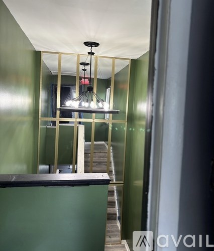 A room with a green wall and a wooden staircase.