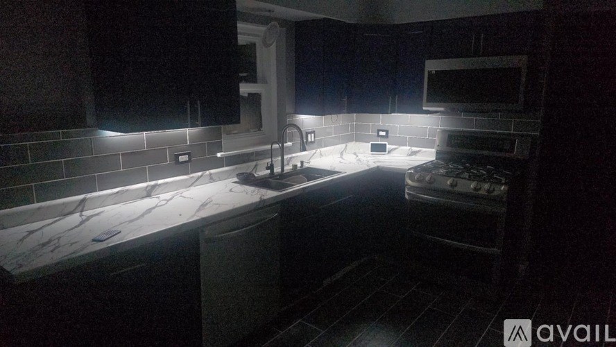 A kitchen with a dark background and a countertop with a sink.