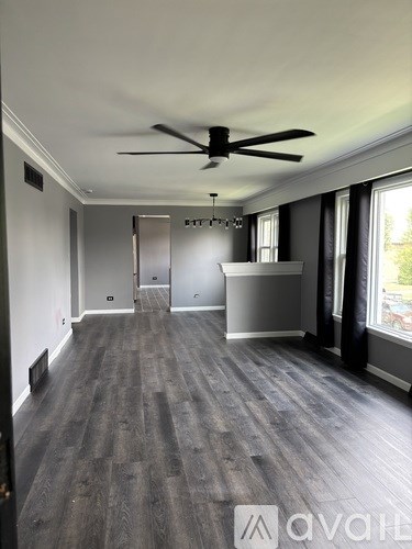 A spacious room with a ceiling fan and wooden flooring.