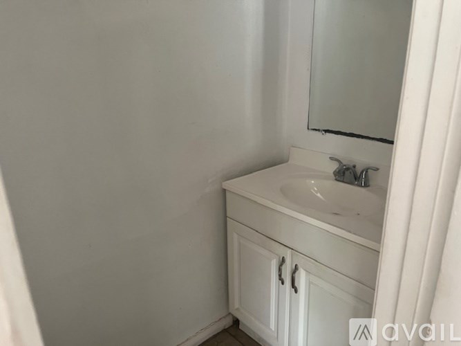 A white bathroom sink with a mirror and a cabinet.