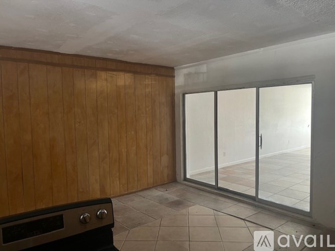 A room with wooden walls and a glass door leading to a balcony.