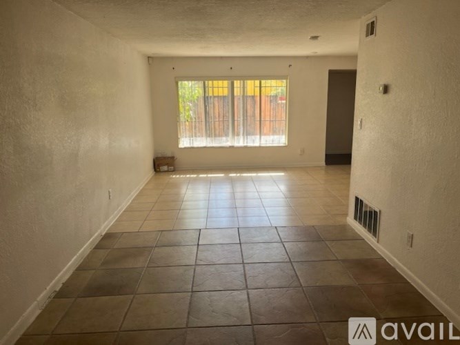A spacious room with tiled flooring and a window with blinds.