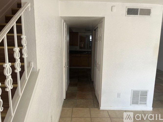 A hallway with a staircase on the left and a doorway leading to a room on the right.