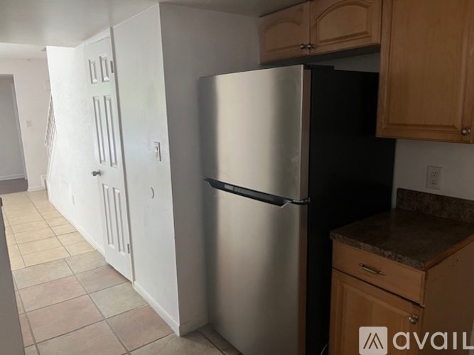 A kitchen with a refrigerator, cabinets, and a counter.