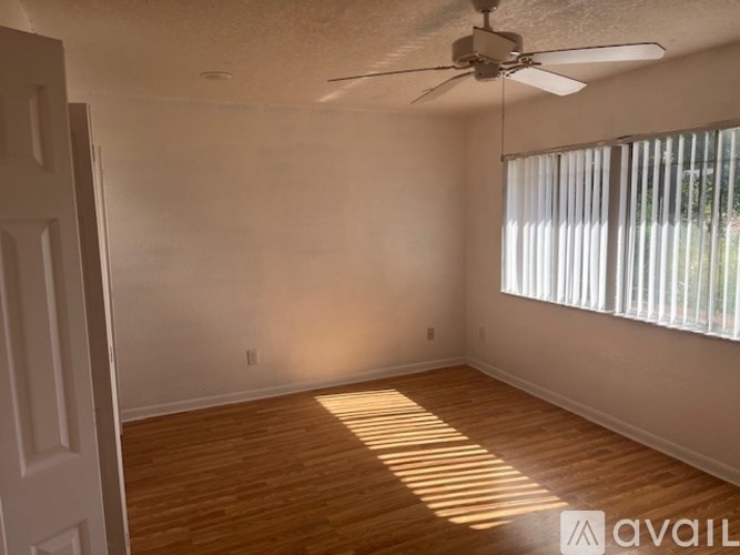 A room with a ceiling fan and a window with blinds.