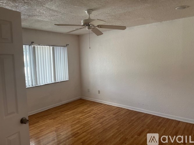 A room with a ceiling fan and wooden flooring.