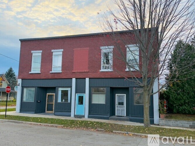 A red and blue building with a tree in front.