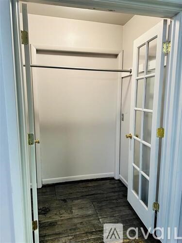 A white door with a glass window is open to a room with a wooden floor.