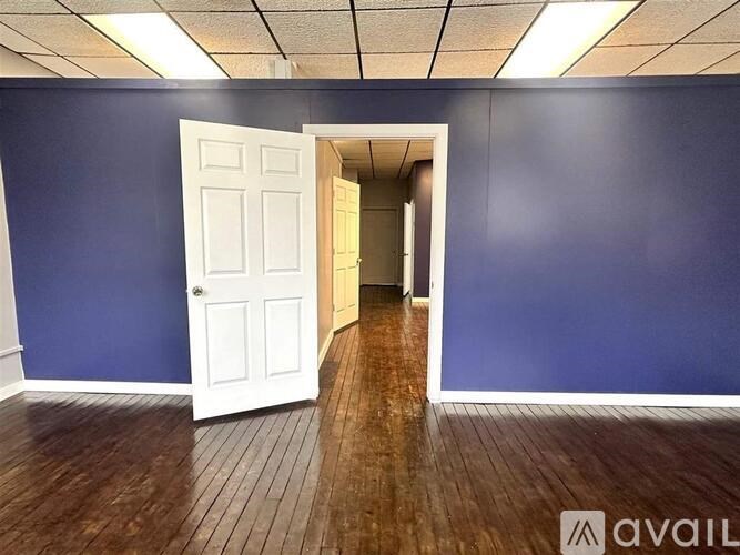 A room with a white door and wooden floor.