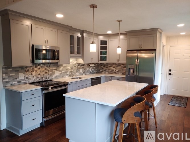 A kitchen with a white island and wooden chairs.